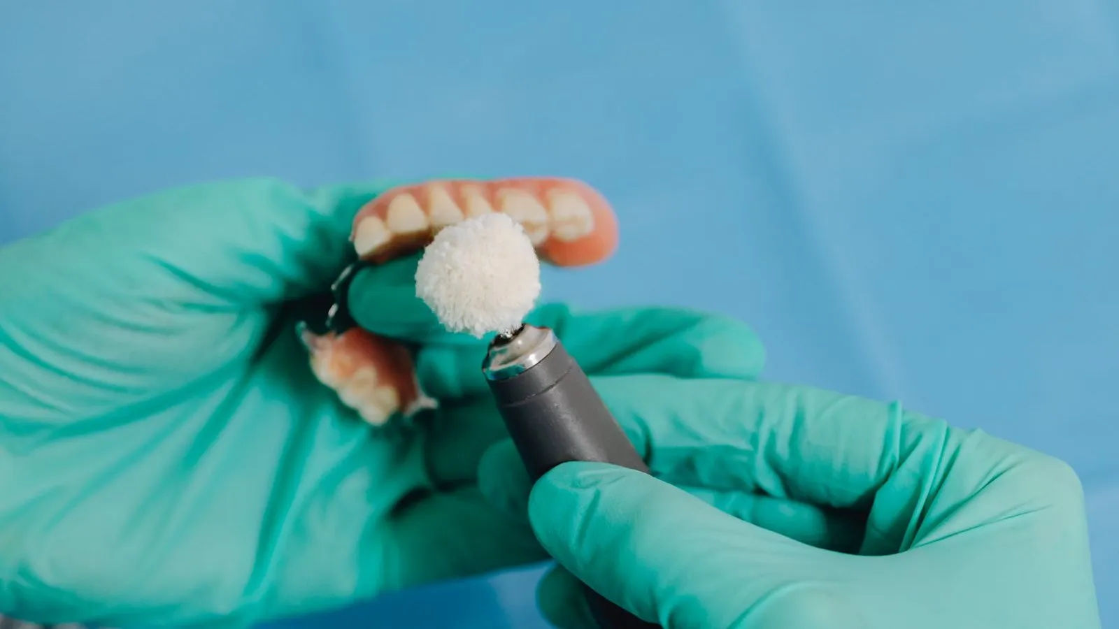 A dental professional polishing a removable denture